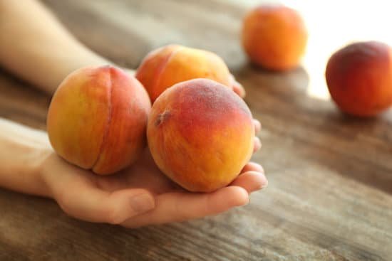 canva hands holding fresh peaches on a wooden background MAD Q42ndW4