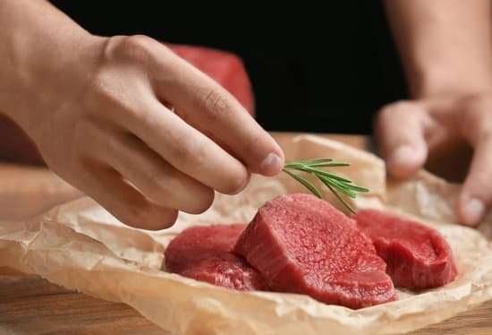 canva man placing a rosemary leaf on raw meat MAD9T71WyU0