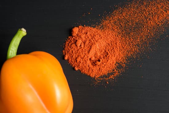canva paprika powder and a orange bell pepper on black background MAESpudnhuA