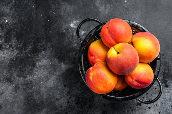 canva peaches in a black colander on the table MAERJ8DDvjc