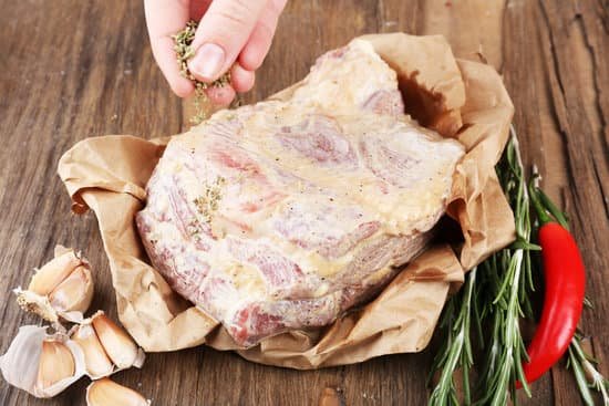 canva person seasoning raw meat on wooden table MAD L384Wyk