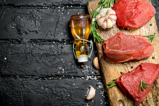 canva raw meat with garlic and rosemary on wooden board