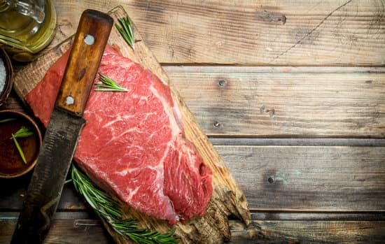 canva raw meat with herbs and knife on wooden board flatlay