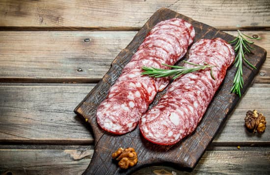 canva sliced salami with rosemary on a wooden board MAEPl1nil0o