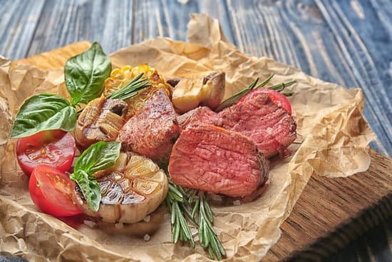 canva tasty juicy meat with vegetables on wooden board MAD9Tw402u0
