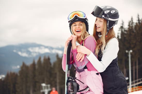 canva two happy women in jacket and helmet with snowboard outdoors MAEWQFpvgQs