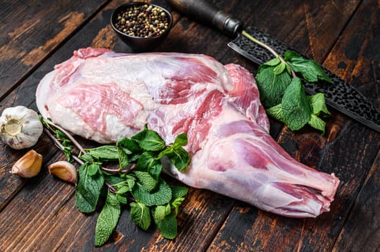 canva whole raw lamb shoulder leg meat with dark wooden table MAEQrYtJcSE