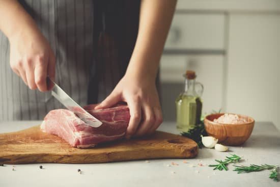 canva wooman hands cutting beef meat on wooden chopping board MAC1CgYSRDo