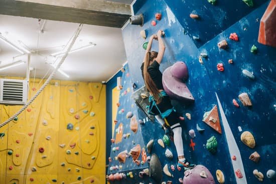 canva young woman climbing a tall indoor man made rock climbing wall MAEAtenvUSs