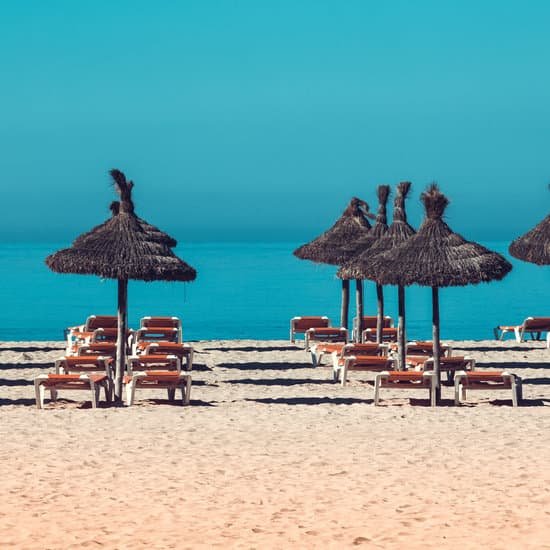 canva beach scenery with parasol and deck chairs. MADBa7dGOoU