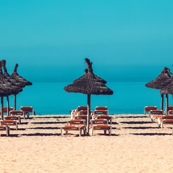 canva beach scenery with parasol and deck chairs. MADBkT2Z4kg