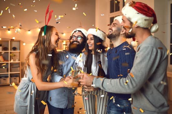 canva cheerful friends clinking glasses during cozy christmas or new year party at home MAELsVZuX0U