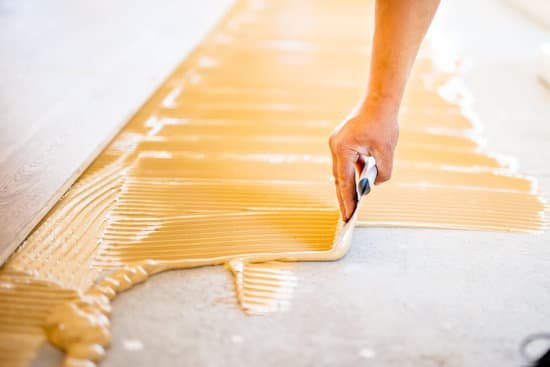 canva close up of hand of worker adding glue during parquet installation MADaAZYjXrs