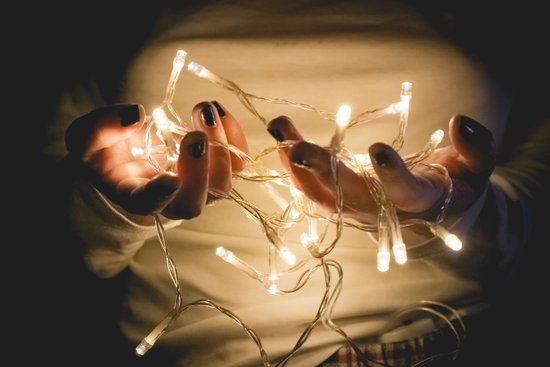 canva closeup photo of person wearing white long sleeved shirt holding turned on string lights MADGwNRFdmk