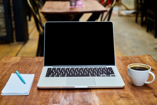 canva coffee and a laptop on a wooden table MADQ5Fnk5ZM