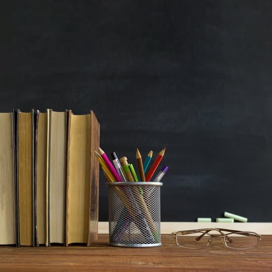 canva glasses teacher books and a stand with pencils on the table on the background of a blackboard with chalk. the concept of the teachers day. copy space. MAEE7kzfjGk