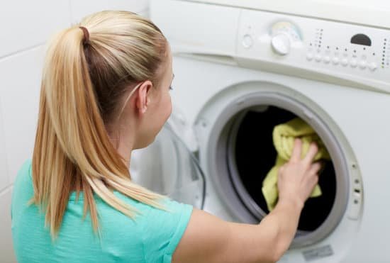 canva happy woman putting laundry into washer at home MABMG0cnpt0