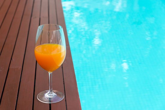 canva orange juice in wine glass on edge the blue sky pool in party luxury hotel thailand MADF06DwkR4