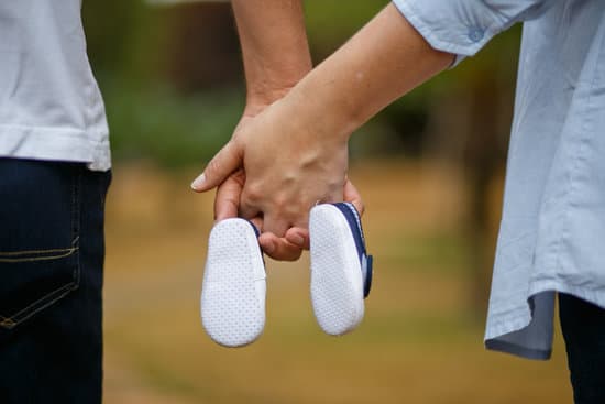 canva parents hands holding baby shoes MADQ4 7rsgc