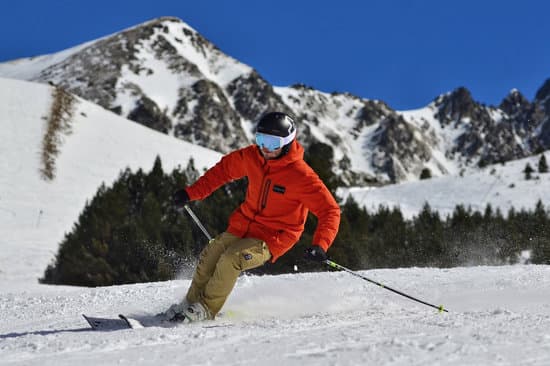 canva photo of a man in an orange jacket and beige trousers skiing