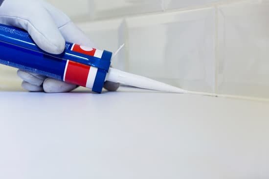 canva plumber applying silicone sealant to the countertop and ceramic tile. home improvement kitchen renovation concept MADesVlksZw