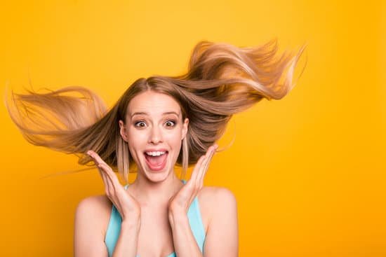 canva portrait of cute straight haired blonde caucasian smiling girl wearing casual blue shirt amazed showing excitement wind blows hair. isolated over yellow background MADapYS wjY