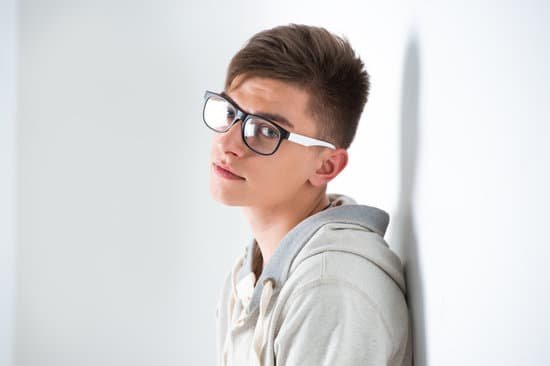 canva portrait of young fashionable man leaning on white wall and wearing glasses. he is trendy fashionable or maybe gay MAAVNGosBfI