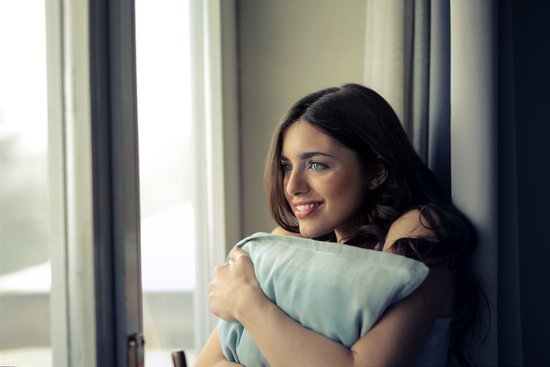 canva woman hugging white pillow beside glass door MADGyfyFaJ0