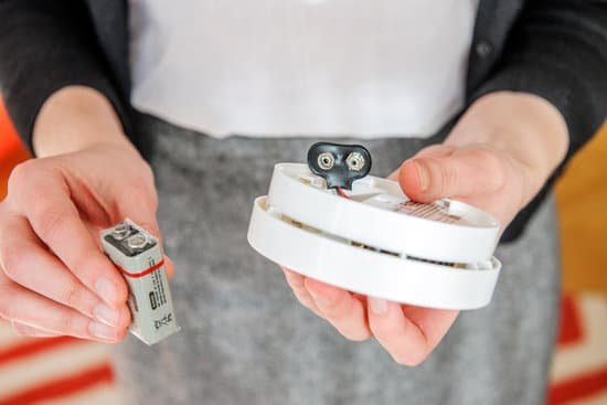 canva woman installing 9 volt battery in smoke detector MAC374sZZck