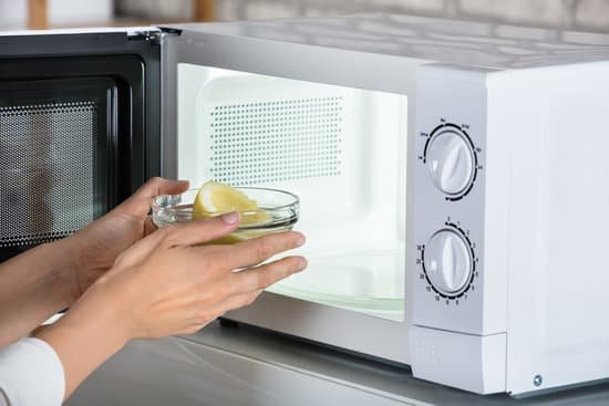 canva woman putting bowl of slice lemon in microwave oven MADer23MeiQ