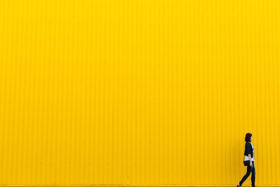 canva woman standing beside yellow paint wall