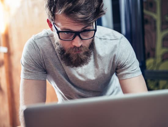 canva young man with glasses and beard using laptop MACF SQCKqA